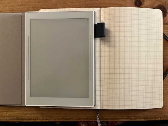 The Supernote on top of an open Moleskine Notebook showing the difference in screen area versus the page size.